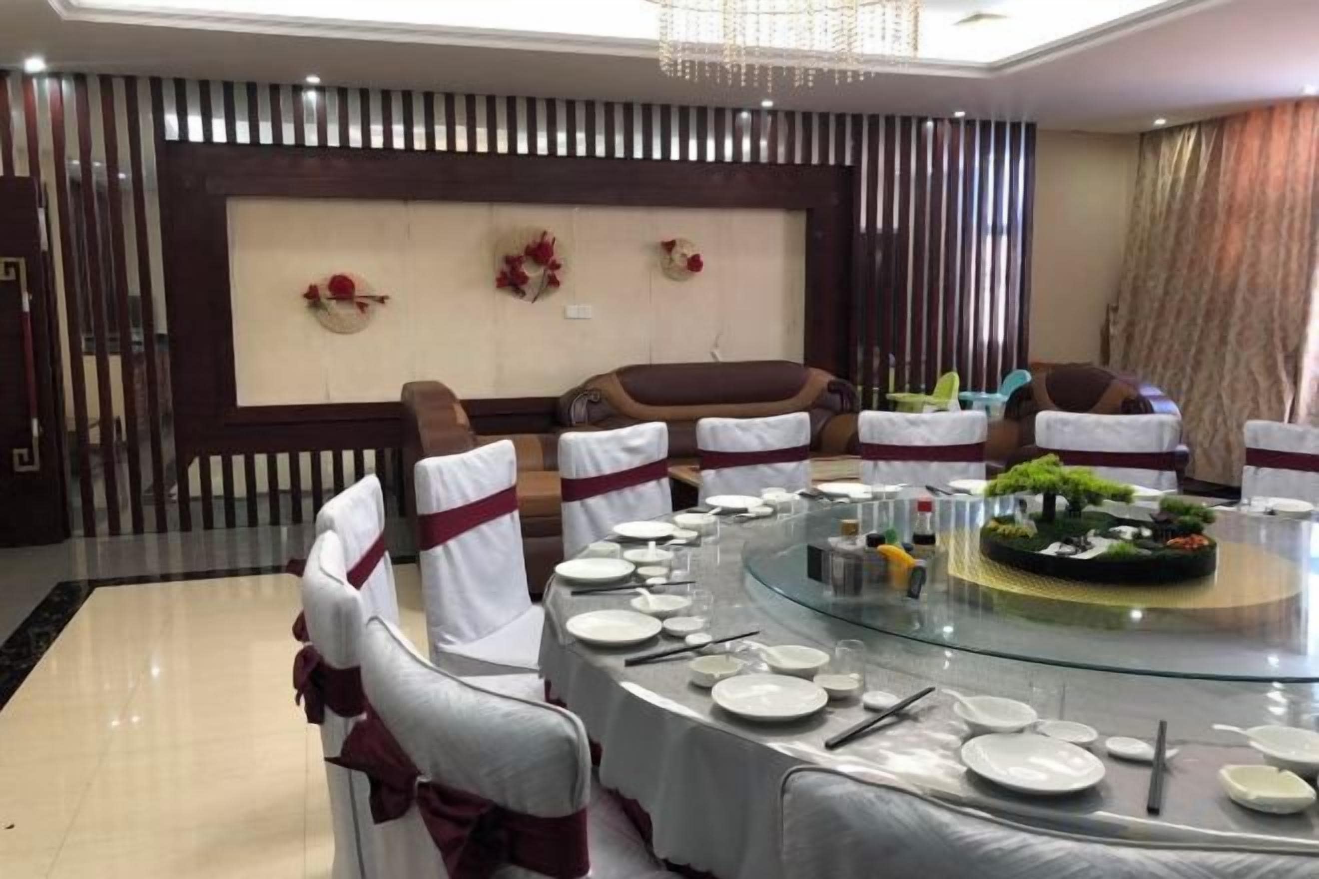 A round dining table set with white plates, silverware, and a centerpiece with greenery and flowers.