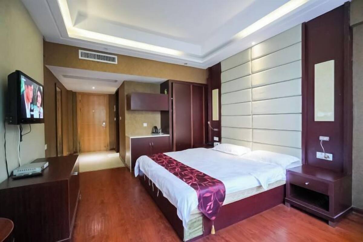 Una habitación de hotel con una cama grande, televisor, escritorio y armario.