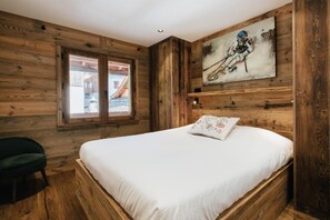 Quarto rústico tipo cabana, com cama, janela e um quadro na parede.