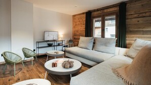 Ein modernes Wohnzimmer mit einer Couch, zwei Sessel, einem Couchtisch und einem Beistelltisch.