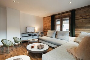 Uma sala de estar moderna com um sofá, duas poltronas, uma mesa de centro e uma mesinha lateral.