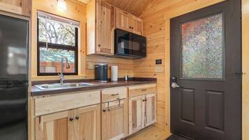 A compact kitchen with wooden cabinets, a microwave, and a sink.
