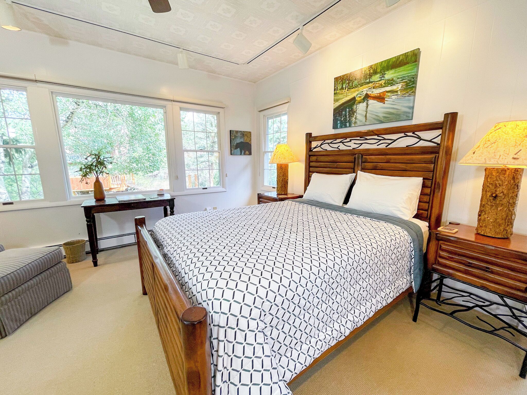 A bedroom with a large bed, a desk, a chair, and a lamp.