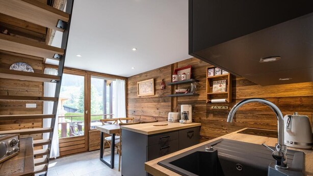 Una cocina moderna con detalles de madera, un lavamanos grande y vistas al exterior.