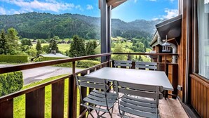 Un balcón con mesa y sillas, con vistas a un paisaje montañoso.