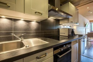 Eine moderne Küche mit Spüle aus Edelstahl, Backofen und Mikrowelle.