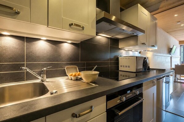 A modern kitchen with stainless steel appliances, a double sink, and a built-in oven.