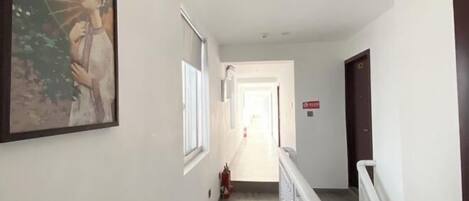 A hallway with a fire extinguisher, a door with a sign, and a framed picture on the wall.
