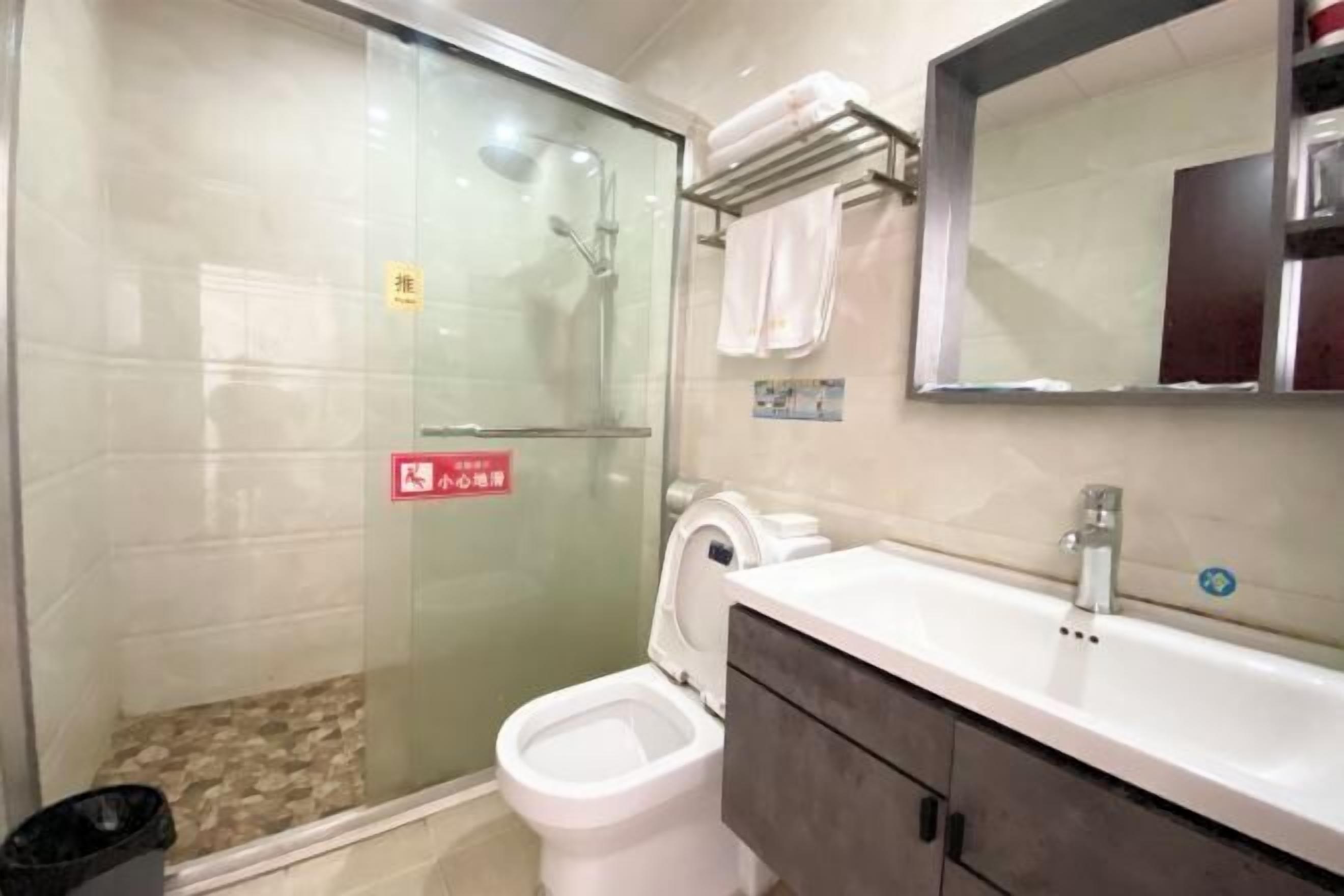 Ein Badezimmer mit Duschkabine, Toilette, Waschbecken und Spiegel.
