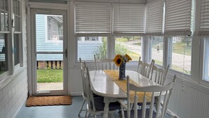 A dining area with a white table and chairs, a ceiling fan, and large windows with blinds. - 4-BdRm Home at Black Point Beach, East Lyme - WiFi + AC, Pet Friendly! (East Lyme)