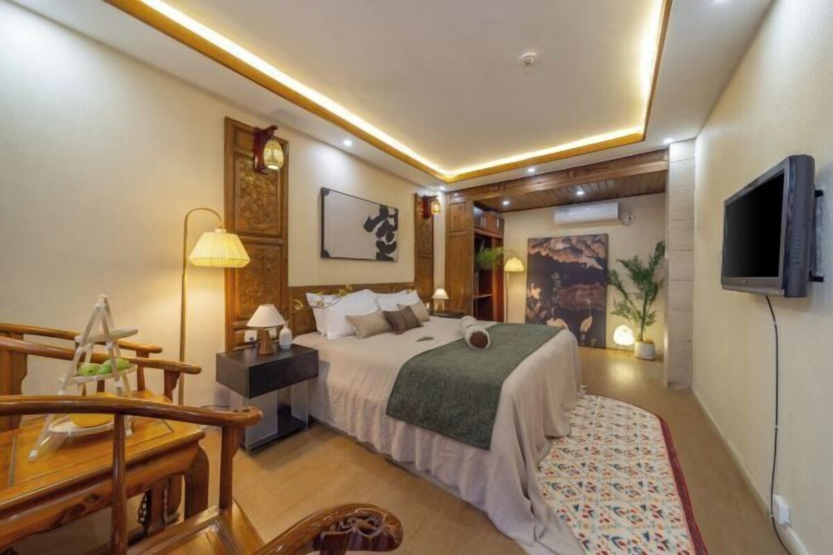 A bedroom with a bed, bedside tables, a TV, and a wooden chair.