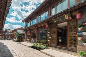 A traditional building with a storefront, wooden architecture, and potted plants. - Home Inn (Zhongyi) (Lijiang)