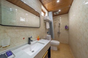 A bathroom with a sink, mirror, toilet, shower, and marble walls. - Home Inn (Zhongyi) (Lijiang)