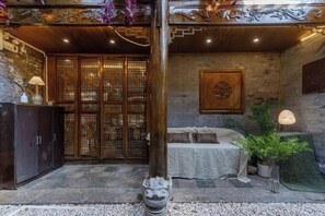 A traditional interior with a wooden door, a sofa, and a potted plant. - Home Inn (Zhongyi) (Lijiang)