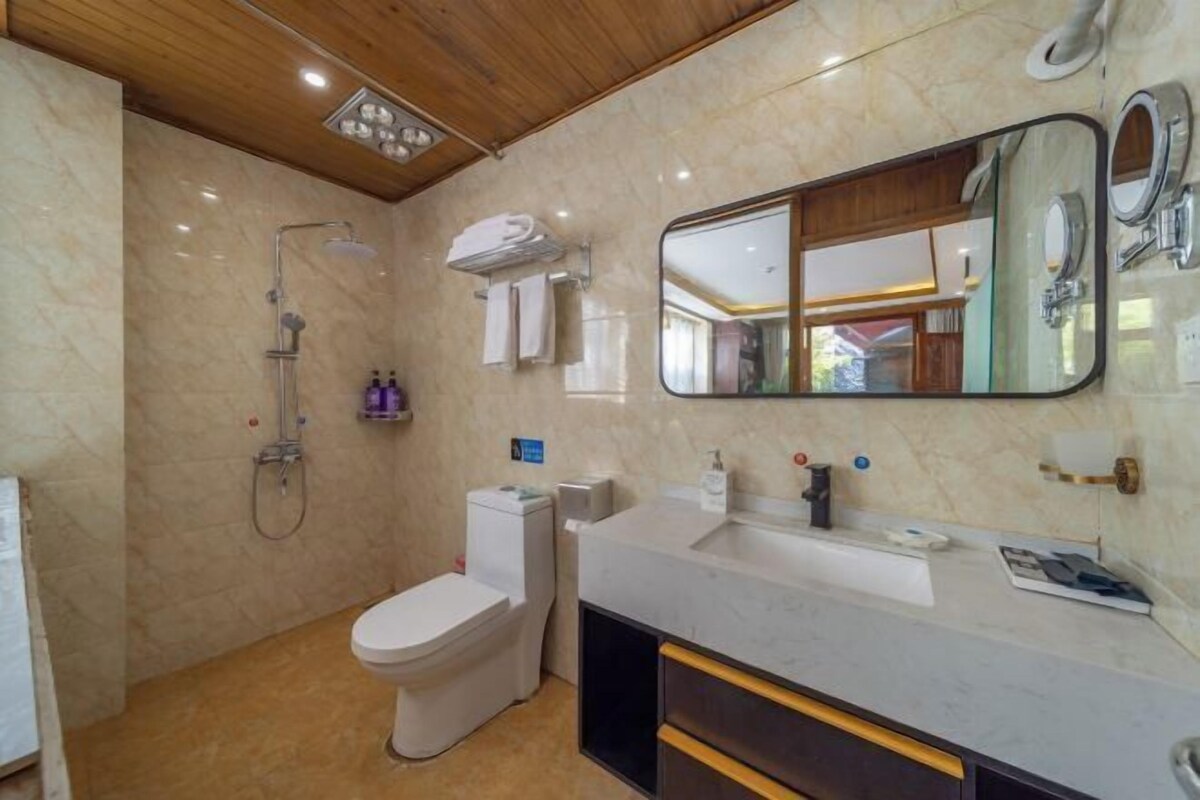 A bathroom with a toilet, sink, mirror, shower, and towel rack.
