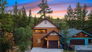 A two-story house with a garage, surrounded by trees and a driveway.