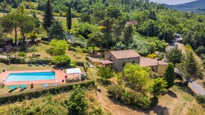 Une villa avec piscine, entourée d’une végétation luxuriante et de collines.