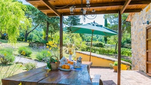 A wooden pergola with a table set for a meal, surrounded by a garden with various plants and flowers. - Fienile by Interhome (Castelnuovo Val Cecina)
