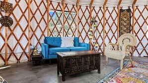 Un interior acogedor con un sofá azul, una mesa de centro de madera, sillas de mimbre y una alfombra estampada.