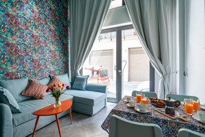 Uma sala de estar moderna com um sofá, uma mesa de centro e uma mesa de pequeno-almoço servida com sumo de laranja e pastelaria.