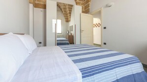 Un dormitorio con cama, espejo y puerta que da a otra habitación.