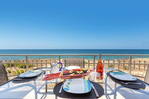 Une table dressée pour deux personnes, avec vue sur la plage et l’océan.