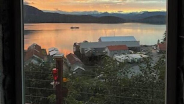 A view of a lake at sunset with buildings and a boat in the foreground.