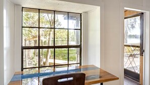 Una habitación con ventanal que da a un jardín, una mesa de madera y una silla.