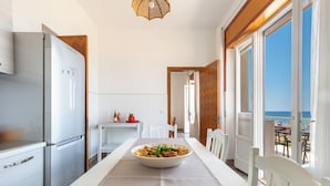 A modern kitchen with a dining area, a view of the sea, and a balcony.