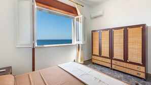 A room with a bed, a wardrobe, and a window with a view of the sea.