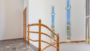 A wooden staircase with marble steps and a view of the outside through windows.