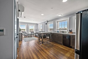 Une cuisine moderne avec un plancher en bois, un îlot central et un réfrigérateur.