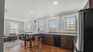 Una cocina moderna con suelo de madera, armarios oscuros y un refrigerador de acero inoxidable.