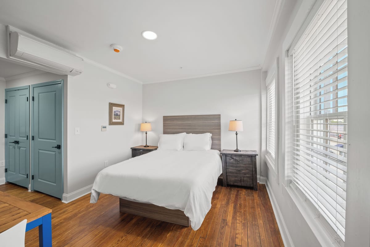 A bedroom with a bed, bedside tables, a wardrobe, and a window with blinds.