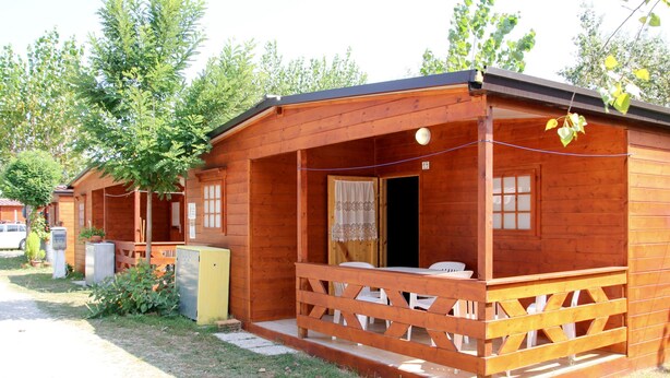 Eine Holzhütte mit Veranda, einem kleinen Tisch und Stühlen.