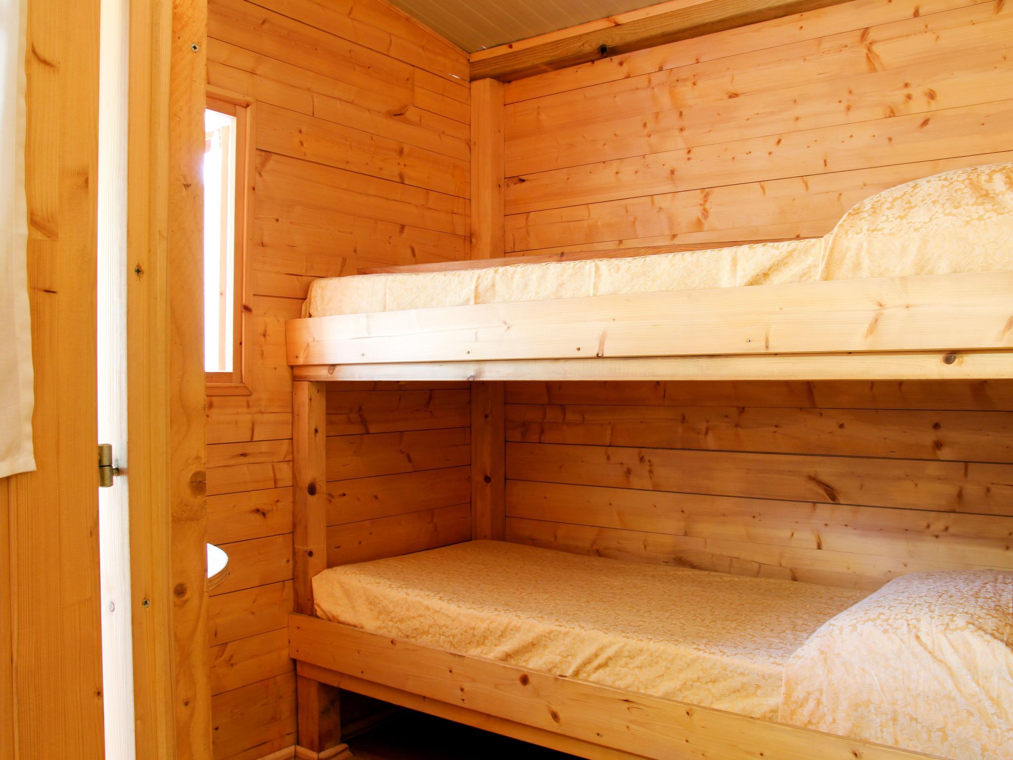 Ein Zimmer in einer Holzhütte mit einem Etagenbett, einem Fenster und einer Tür.