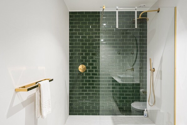 A modern bathroom with a glass-enclosed shower, a white sink, and a toilet.