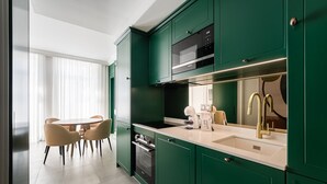 A modern kitchen with green cabinetry, a built-in microwave, and a gold faucet. - GuestReady - Stylish stay with a balcony (Porto)