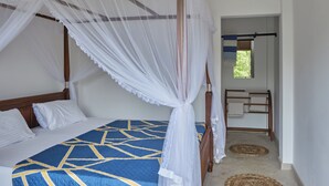Un dormitorio con cama, dosel, cabecera de madera, mesita de noche y ventana con vistas a zonas verdes.