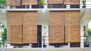 Un edificio de varios pisos con grandes contraventanas de madera, balcones con plantas y una escalera que lleva al piso superior.