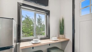 Kompakti keittiö, jossa on ikkuna, ruostumattomasta teräksestä valmistettu jääkaappi ja puinen työtaso.