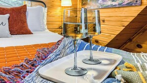 A cozy room with a bed, a wooden wall, a painting, and two glasses on a tray. - VIEWS, hot tub, firepit, WIFI and Outdoor Speakers (Bryson City)