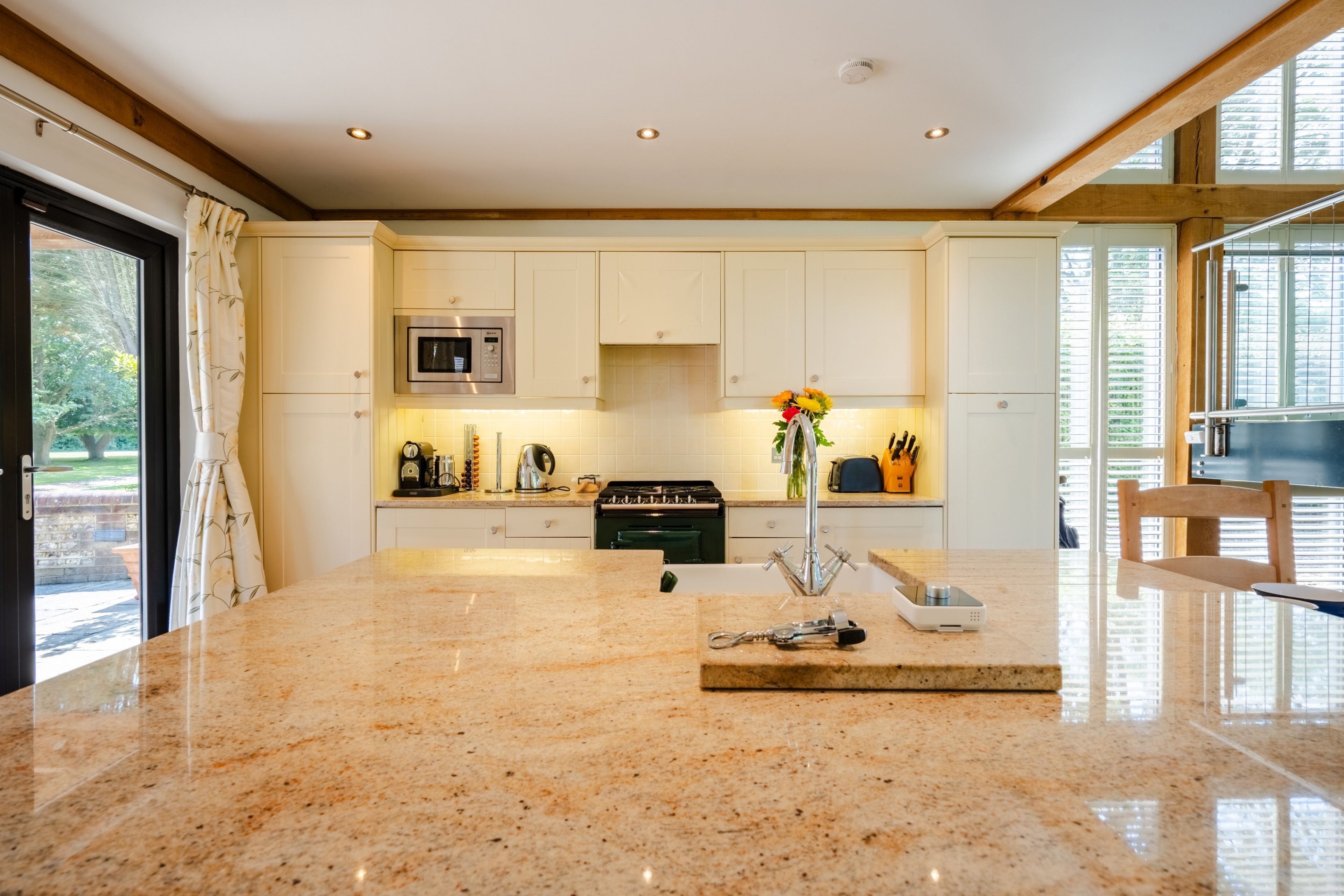 A modern kitchen with white cabinets, a granite countertop, and a stainless steel range hood.