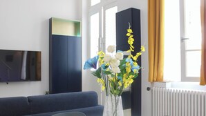 Un salon moderne avec une table à manger ronde, un canapé bleu et un vase décoratif orné de fleurs.