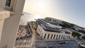 A coastal cityscape with a historic building, a modern structure, and a busy street with vehicles and pedestrians. - Charming Apartment at 10mn du Vieux Port (Marseille)