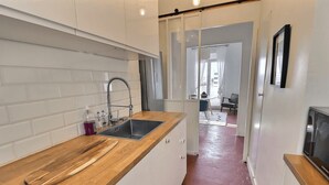 A modern kitchen with white cabinets, a wooden countertop, a sink, and a stainless steel faucet. - Charming Apartment at 10mn du Vieux Port (Marseille)
