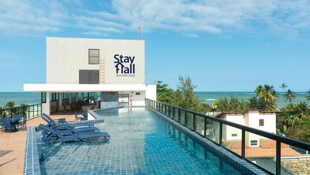Een hotel met een zwembad, uitzicht op de oceaan en een bord waarop staat 'Stay Hall short term rental'.