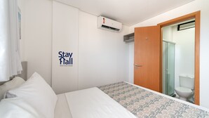 Hotelkamer met een bed, een kledingkast, een airconditioning en een badkamer met toilet en douche.