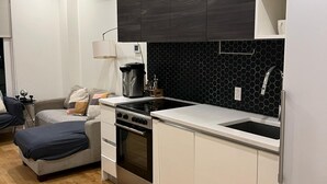 A modern kitchen with white cabinetry, a black backsplash, and a wooden floor. - Charming 2-bedroom  2 bath ! apartment in Brooklyn   Gym laundry and  parking ! (Brooklyn)
