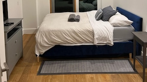 A modern bedroom with a bed, a desk, and a window with blinds. - Charming 2-bedroom  2 bath ! apartment in Brooklyn   Gym laundry and  parking ! (Brooklyn)